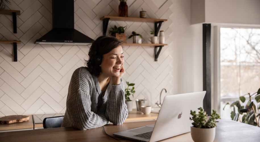 smiling woman talking via laptop in kitchen