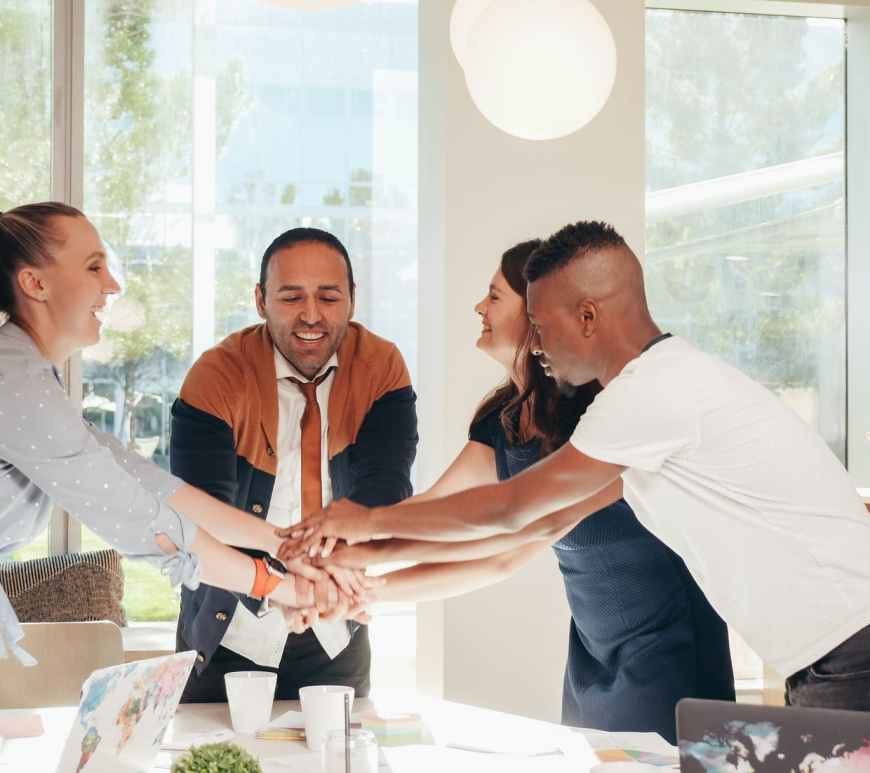 smiling multiracial coworkers with hands together in office